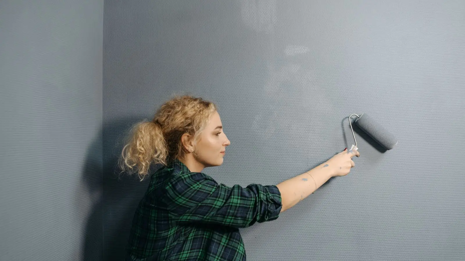 Application au rouleau d'une peinture mate sur un mur de salon