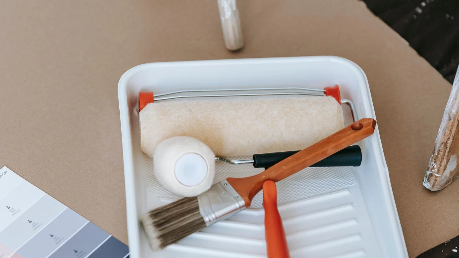 Bac à peinture, rouleau et nuancier de couleurs posés sur un plan de travail