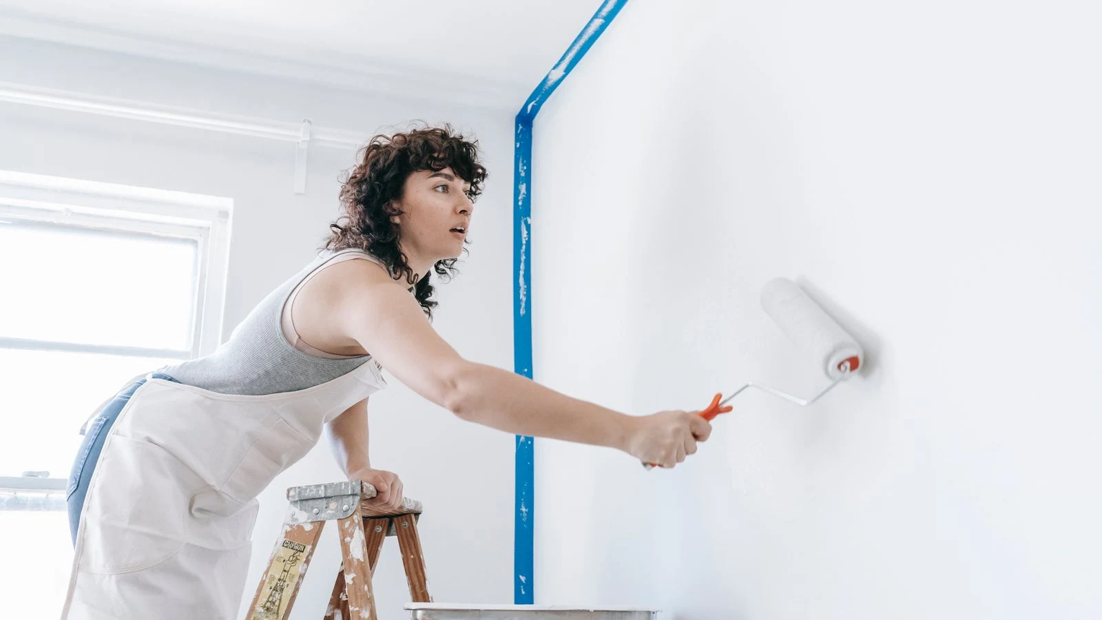 Artisan appliquant une peinture claire dans une pièce vide